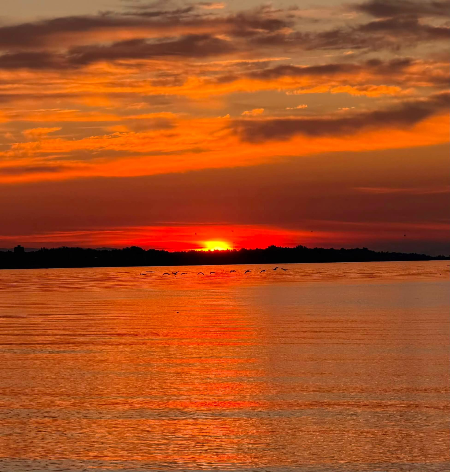 Vivid orange sunset reflected across the water